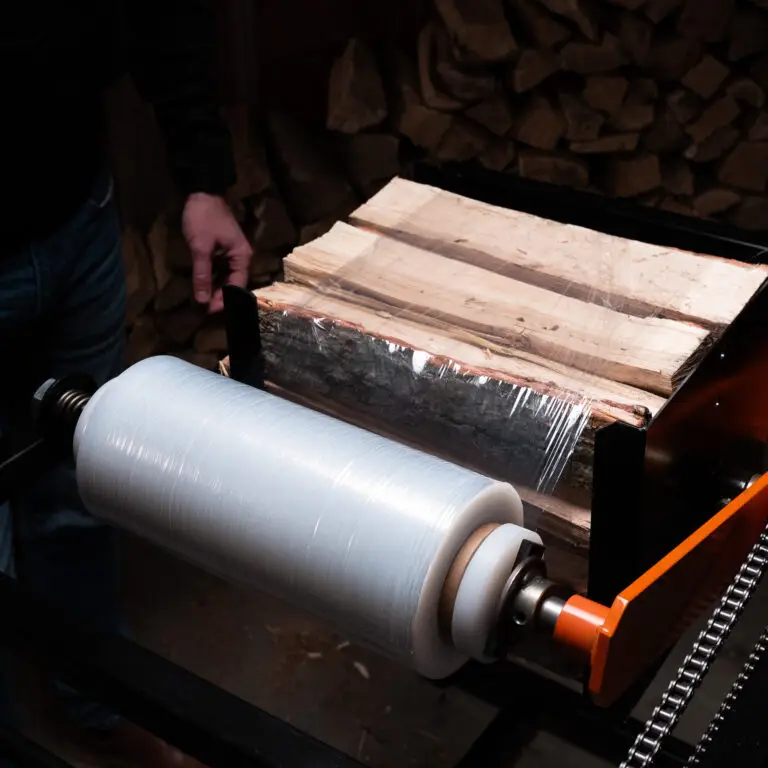 An image of a firewood bundler in action, showcasing neatly stacked firewood being securely wrapped with plastic. A person is operating the bundler, preparing bundles for sale, emphasizing how the tool helps streamline the process and increase profitability for firewood sellers.