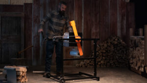 Homesteader using the IronEmber firewood bundler to create neatly wrapped firewood bundles next to a stacked rack built with IronEmber rack brackets.