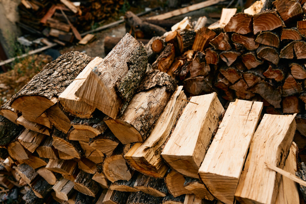 Stacks of split firewood piled on the ground, prepared for drying and sale in a new firewood business